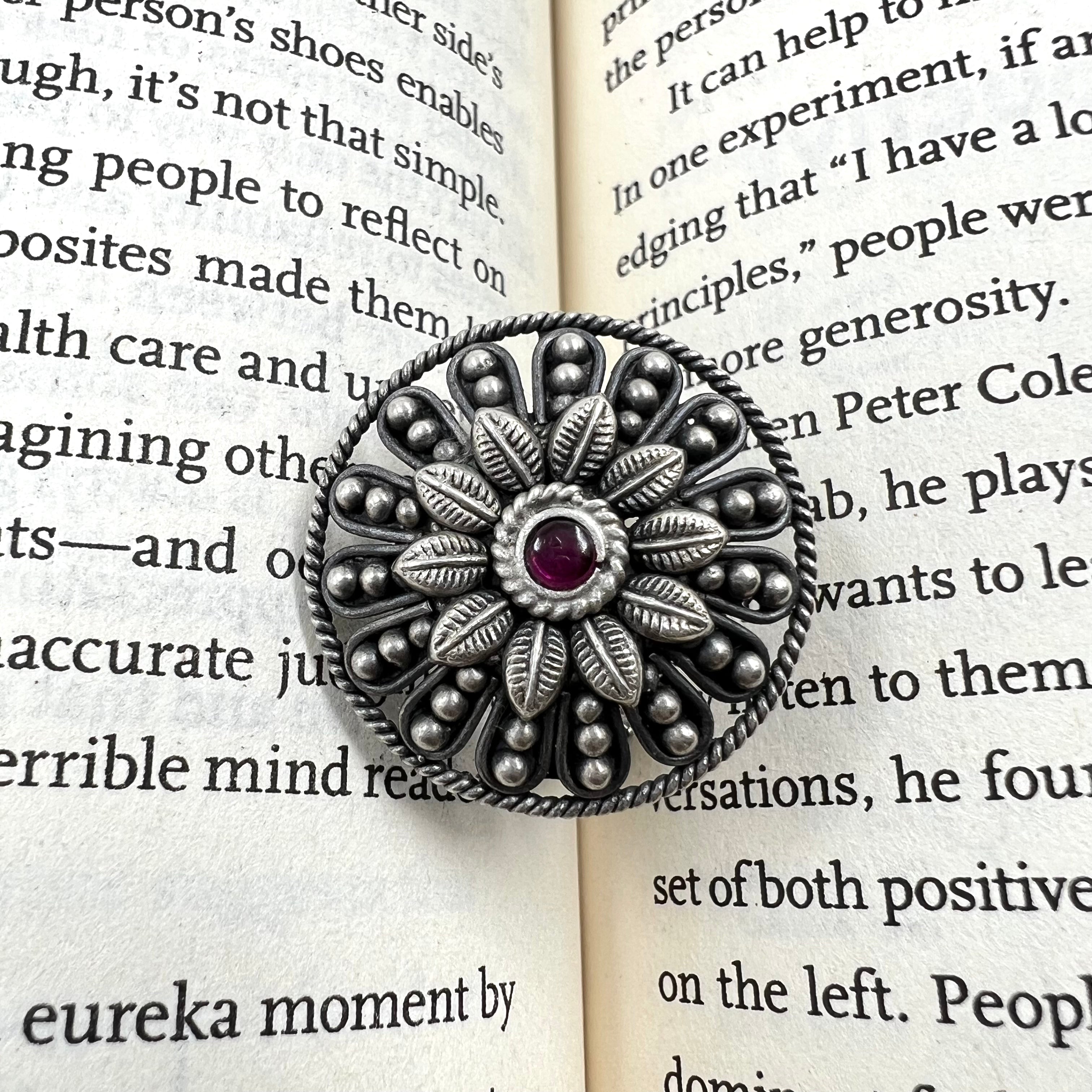 Silver floral brooch with a red gemstone 