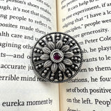 Silver floral brooch with a red gemstone 